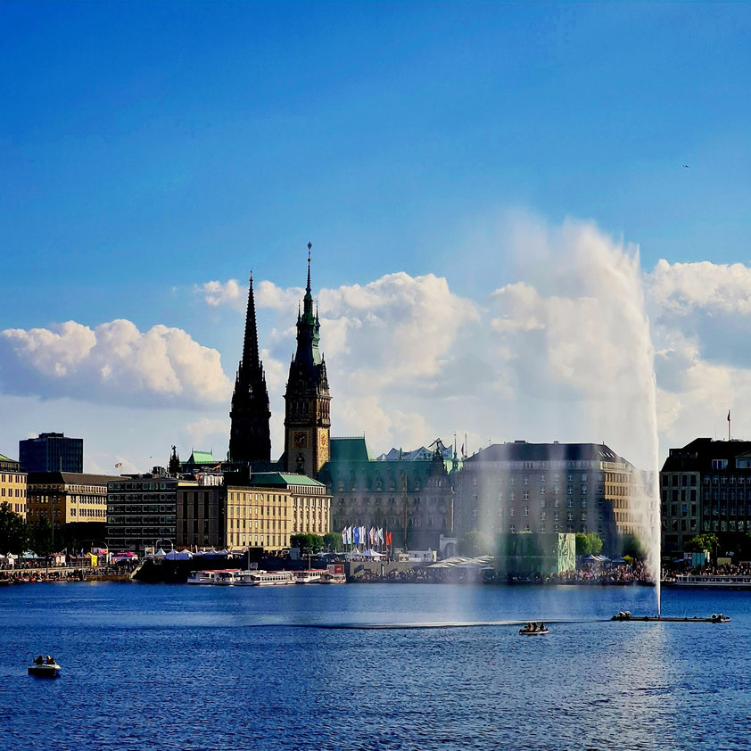 Binnenalster mit Alsterfontäne, im Hintergrund der Rathausturm (rechts) und daneben der Turm der Hauptkirche St. Petri (links)