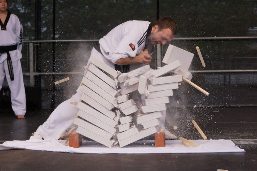 Taekwondo-Meister zerschlägt Betonplatten mit seinem Ellenbogen für eine Vorführung auf einer Bühne.