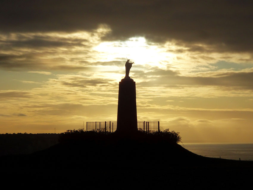 Sur la falaise, la statue tournée vers la mer