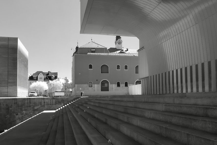 Die ehemalige Zollwerfthalle in Würzburg zeigt sich in Schwarz-Weiß als ein Mix aus moderner und traditioneller Architektur. Eine breite Treppenanlage führt zu einem geschwungenen Gebäudeteil des Heizkraftwerks.