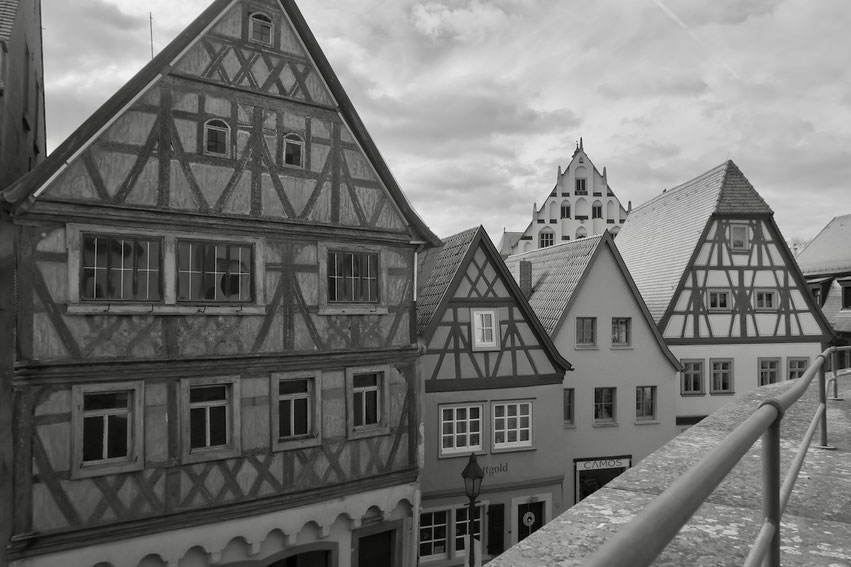 Das Markthaus in Dettelbach als prägendes Element einer Reihe von traditionellen Gebäuden mit markanten Giebeln und Fachwerkstrukturen. Die Schwarz-Weiß-Aufnahme betont die Textur der Fassaden und das historische Ambiente der unterfränkischen Altstadt.