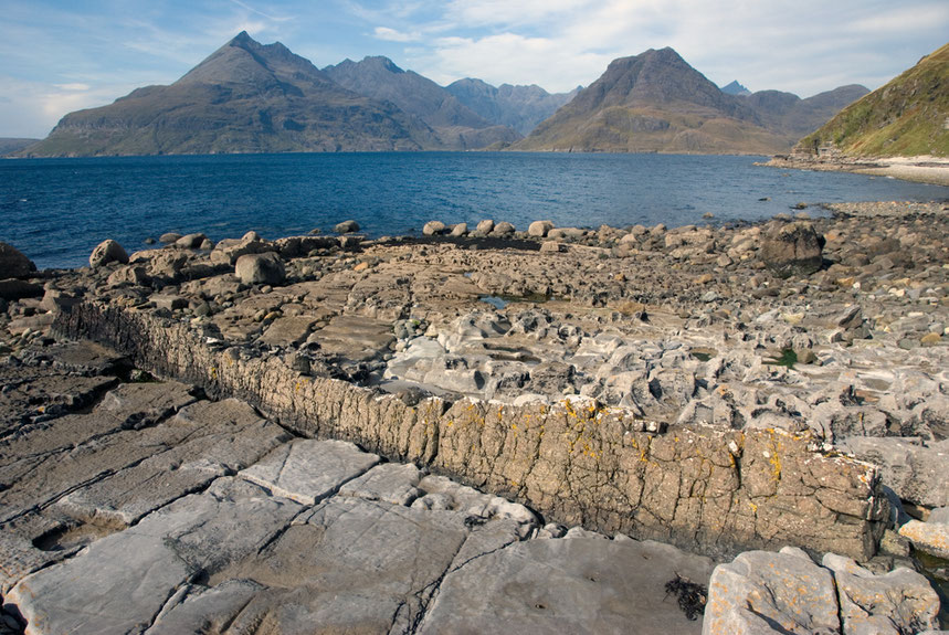 The Cuillin massif on the Isle of Skye from the north of Elgol with a fine dyke in the foreground in the Jurassic limestoones and mudstones in the foreground. 