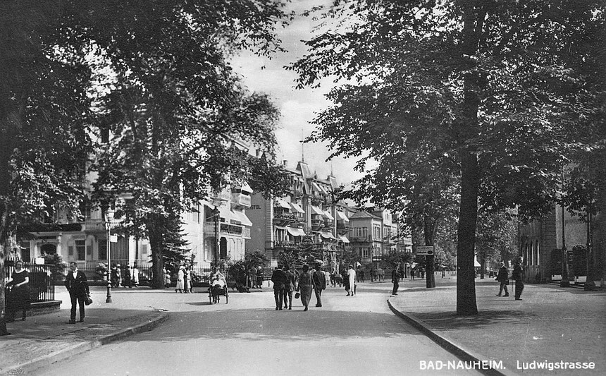 Ludwigstrasse - Einmündung Bahnhofsalle: rechts die Verwaltungsgebäude des Sprudelhofes, gegenüber Villa Langsdorf, Hotel Bristol, Hotel-Café-Conditorei König in den 1920ern - Postkarte: Online-Museum