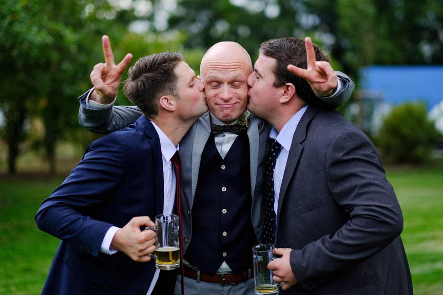 hochzeitsfotograf oer-erkenschwick, hochzeitsshooting, bräutigam wird von zwei seienr best men geküsst