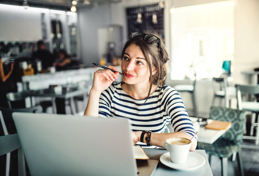 Junge Frau sitzt mit Notebook im Cafe