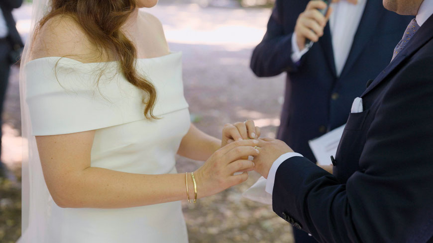 Bride and groom exchange the rings during their outdoor ceremony under the trees in France