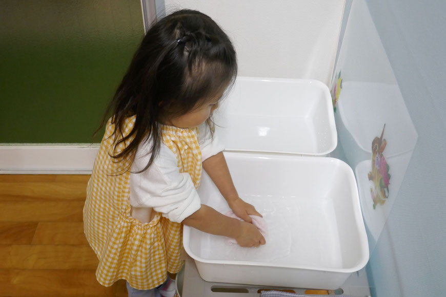 幼児教室の親子で学ぶ２歳児コースで、食事の準備で机を拭くためにふきんを濡らしています。