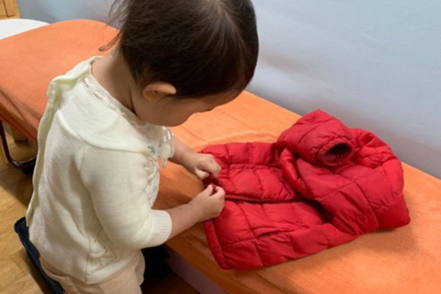 2歳児が入室時に自分で上着をたたんでいます。