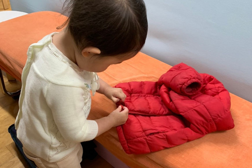 モンテッソーリ教育の日常生活の練習により、自分で上着をかたづけることができるようになった1歳児です