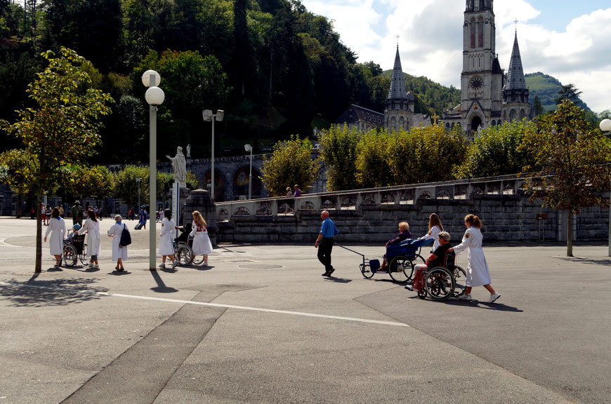 Hier in Lourdes wird die Aufforderung zur Nächstenliebe in die Tat umgesetzt: Freiwillige Helfer transportieren Kranke
