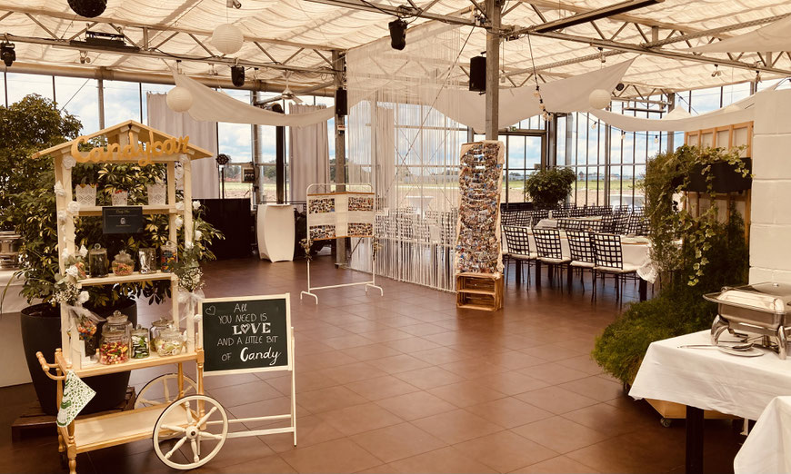 Festlich dekorierter Wintergarten im Jägers Gewächshaus Nürnberg mit Candybar und DJ-Equipment für stilvolle Hochzeitsfeier