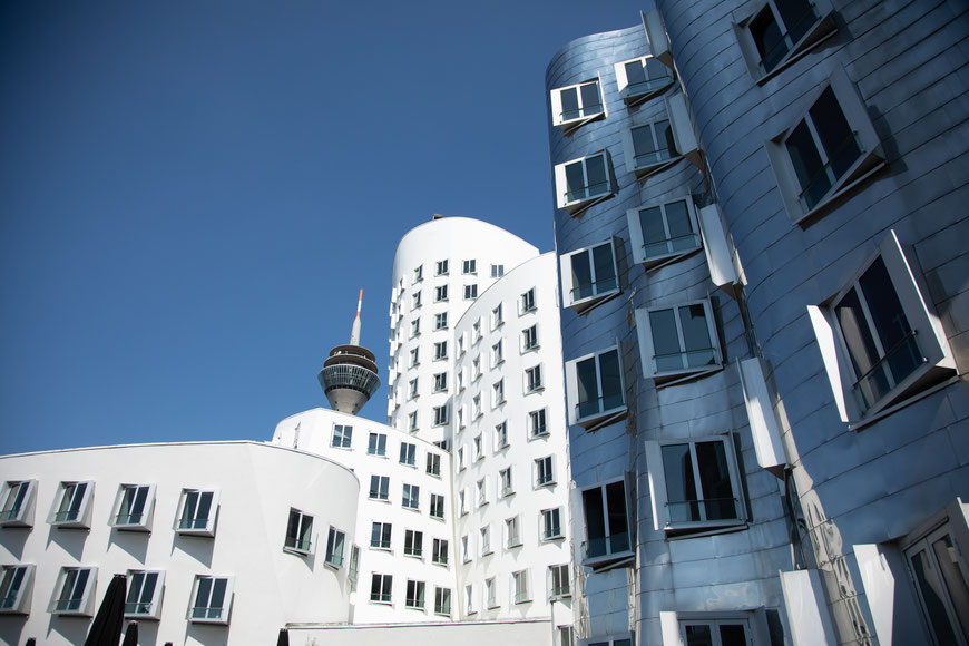 Zwei der Gehry-Bauten im Medienhafen mit der Spitze des Fernsehturms.