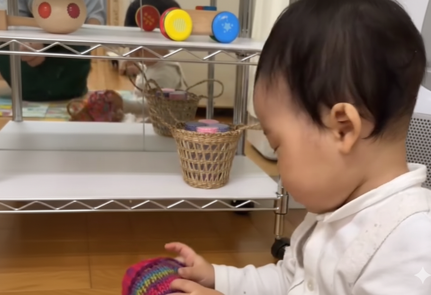 0歳児がリースの落ち葉を触って感触を楽しんんでいます。