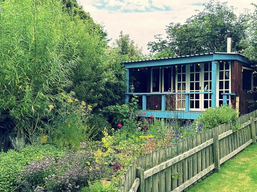 Handmade garden den built from reclaimed timber with covered deck and metal roof