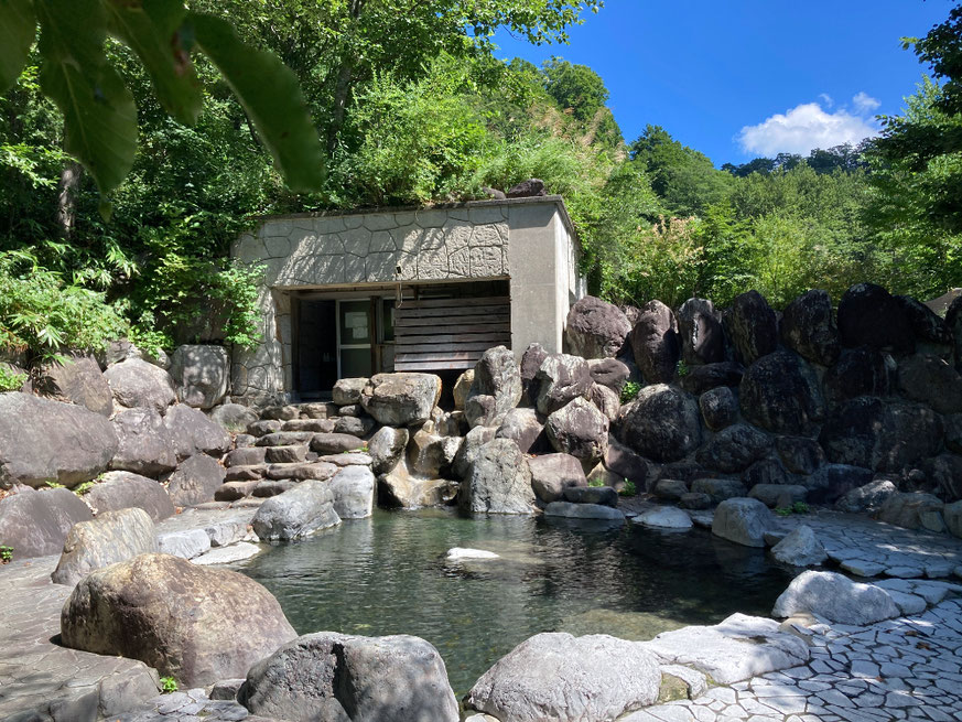 野趣あふれる源泉かけ流しの露天風呂。写真手前が男湯で奥の石積みの向こうに一段高くなった女湯がある