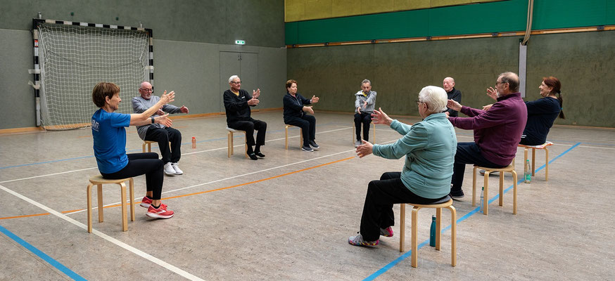 Lungensport-Gruppe des BSV Achim macht gemeinsam Armübungen im Sitzen in der Turnhalle.