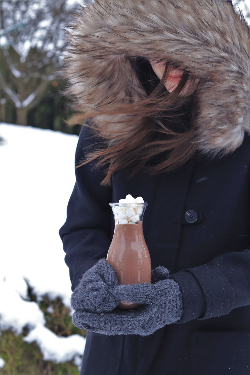 Mädchen in Winterjacke mit heißer Schokolade