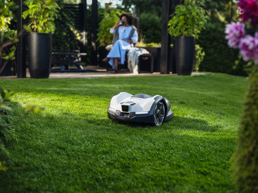 Ein Husqvarna Automower schneidet das Gras im Hinterhof eines modernen