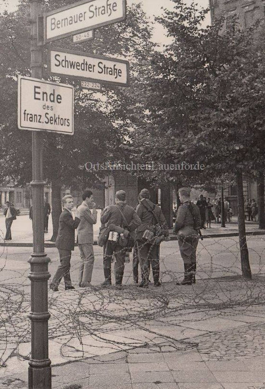 13. August 1961, 07:00 Uhr. Schwedter- Ecke Bernauer Strasse. Stacheldraht ist gezogen worden und bewaffnete Volksarmisten bewachen die Sektorengrenze