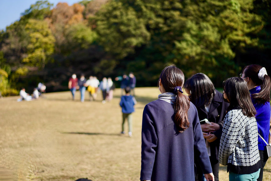 屋外の自然を感じながら、芝生を歩いて集まるグループ。