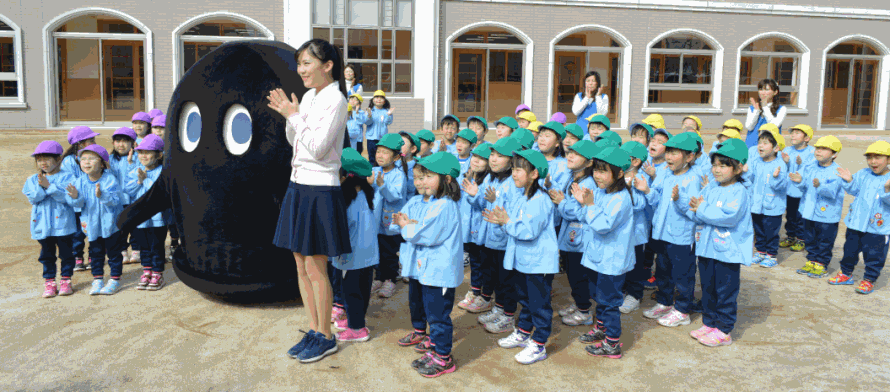 幼稚園にキャラクター（れーべー）が遊びに来て、子どもたちが園庭に集まって並んだところ