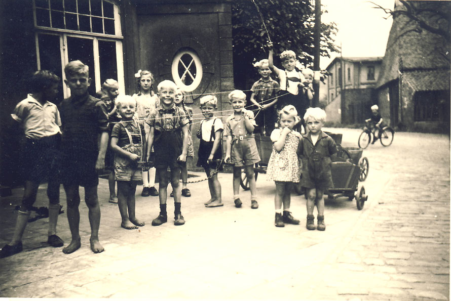 1952: Kinder vor der Bäckerei Koldeweyh auf der Dorfstraße. Im Hintergrund der Hof Budelmann mit der Motormühle.13