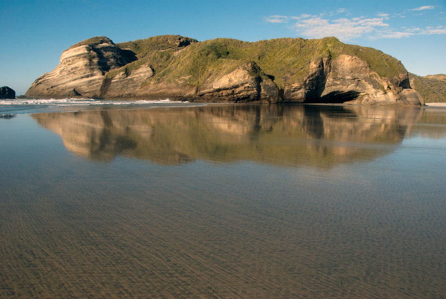 Brilliant reflections at Wharariki Beach in the film of seawater overlying the tidal sands.