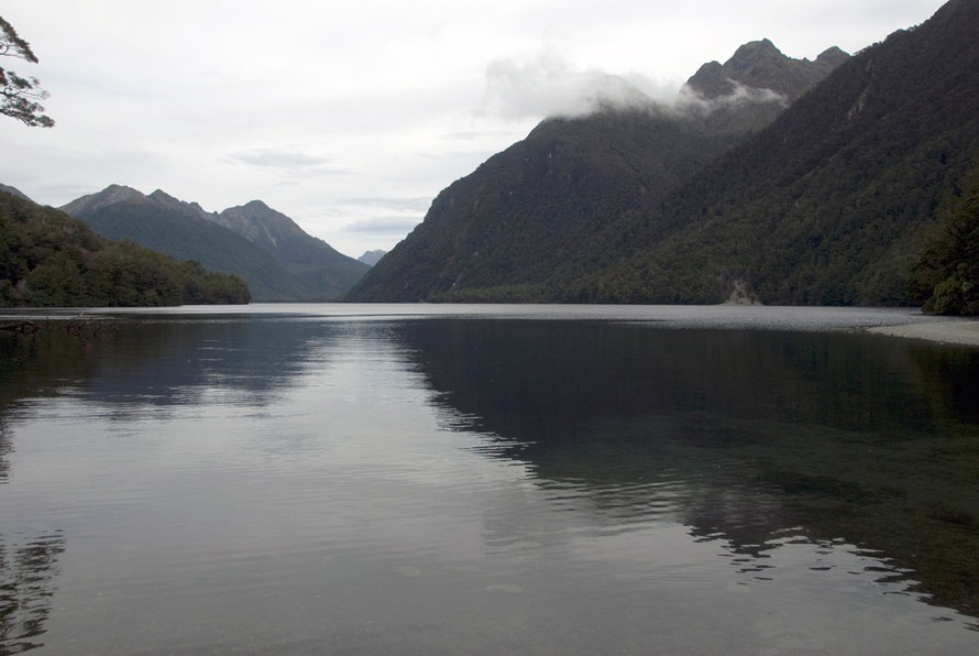 The inky waters of Lake Gunn (480m) on the Milford Road looking south to Melita Peak. Highway 94 snakes through the beech forest on the left hand side of the lake. 