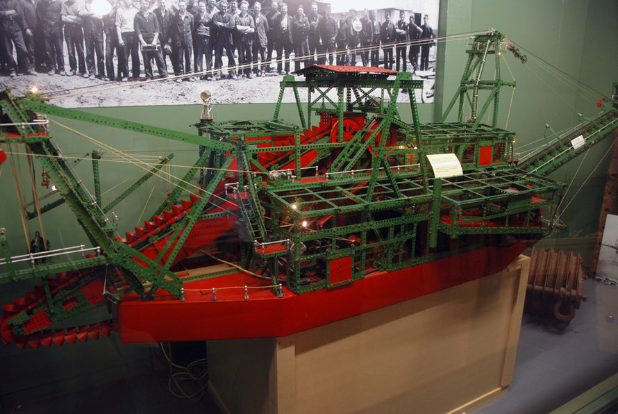 The giant Meccano model of Gold Dredger built by Blake Huffam with a photo of the workers who used to run the real-life dredger (Hokitika Museum)