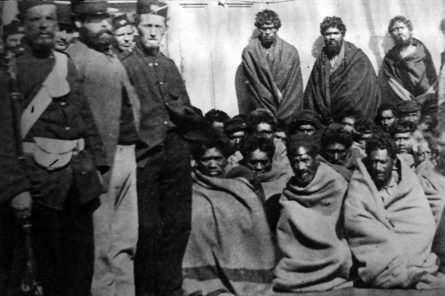 Maori prisoners, members of the Hauhau church, under guard on board a prison hulk in Wellington Harbour, 1866. The prisoners were captured at Wereroa Pa, Waitotara, 20 miles north of Wanganui.