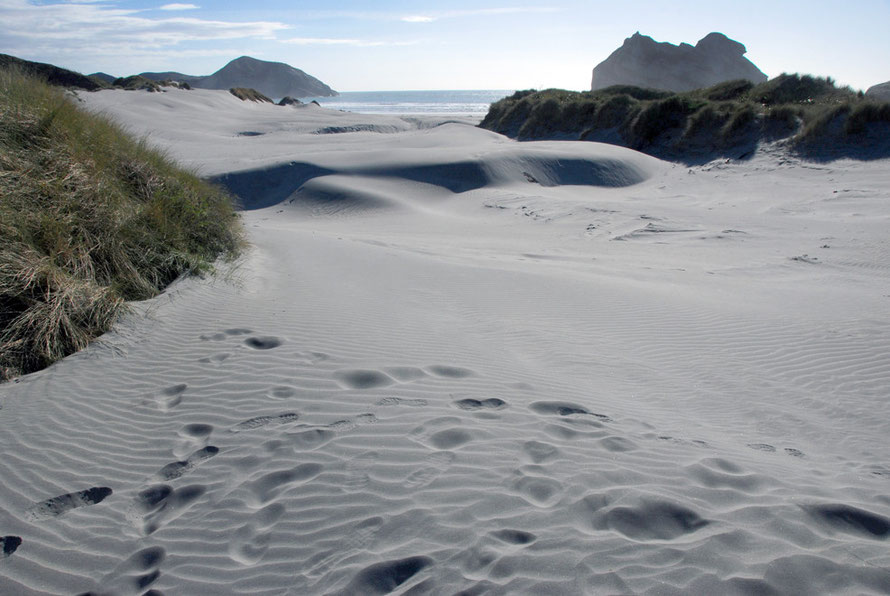 The fine wind blown sands of Wharariki Beach and the distant Archway Islands.