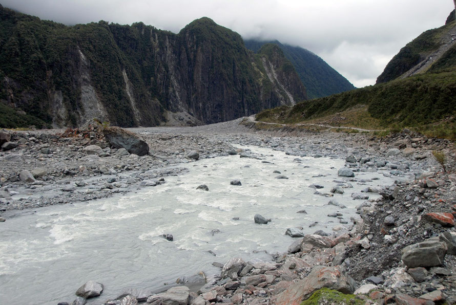 The cloudy waters of the glacier fed stream in the Fox Glacier valley and rock- and tree-fall scars on Cone Rock.