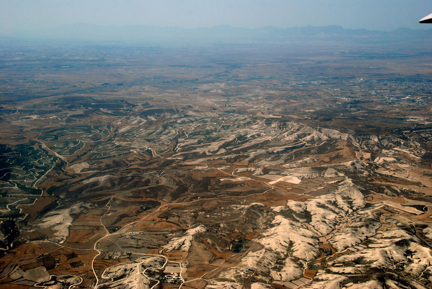 Looking out across the eastern Mesaoria in June 2012.  Marl hills and small wheat fields in the foreground with Atheniou in the middle right distance and the Kyrenian hills in background