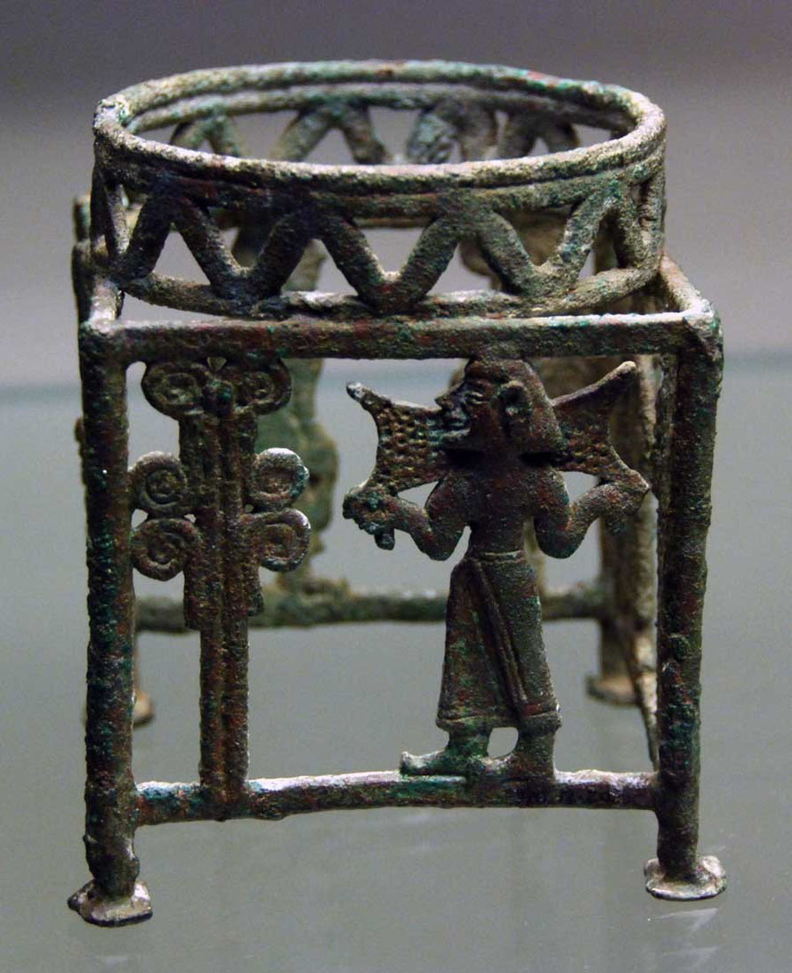 A bronze four sided stand showing a man carrying a copper ox-hide ingot and tree.  12th Century BC, possibly from Kourion, British Museum