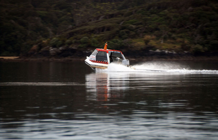 The first water taxi of the moring heads out to Ulva across the glassy waters of Paterson Inlet.