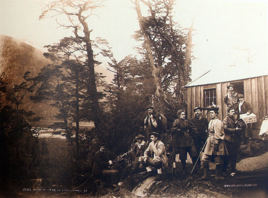 A mixed group of Victorian hikers/trampers prepares to strike out on the Milford Track from this hut at the head of Lake Te Anau. It looks as if four of the party are guides or porters. (Burton Bros, 1895 Turnbull C