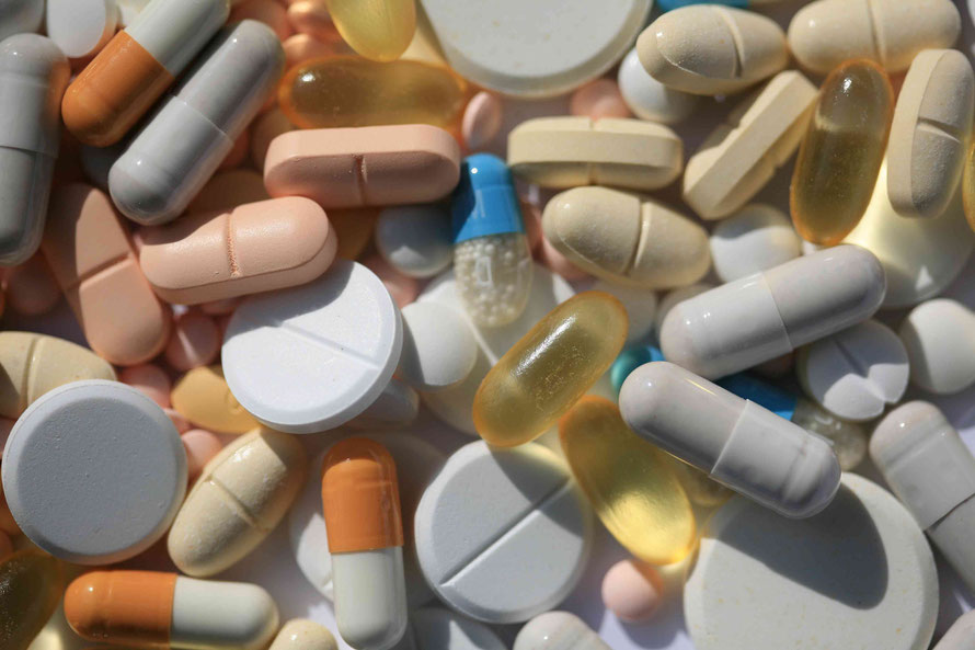 Viele Tabletten, Pillen und Kapseln liegen durcheinander auf einer Fläche.