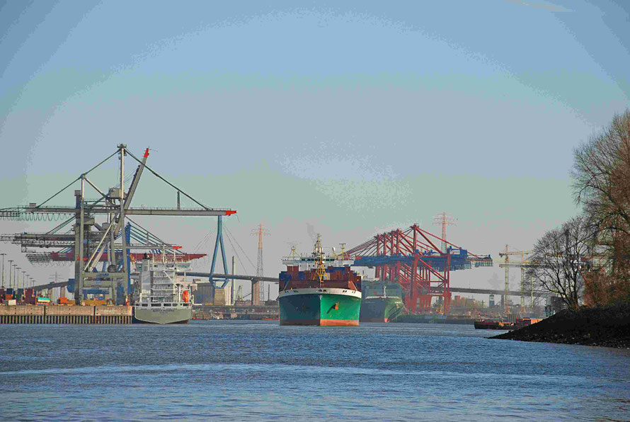 In einem Hafen sind Containerbrücken und Containerschiffe zu sehen.