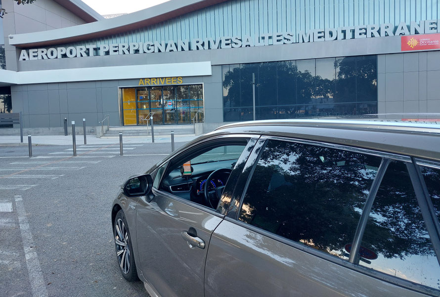 Voiture de VTC premier plan devant l'aéroport de Perpignan Rivesaltes Méditerranée comme un taxi avec Roger Corbière RC VTC Narbonne, transport à petit prix