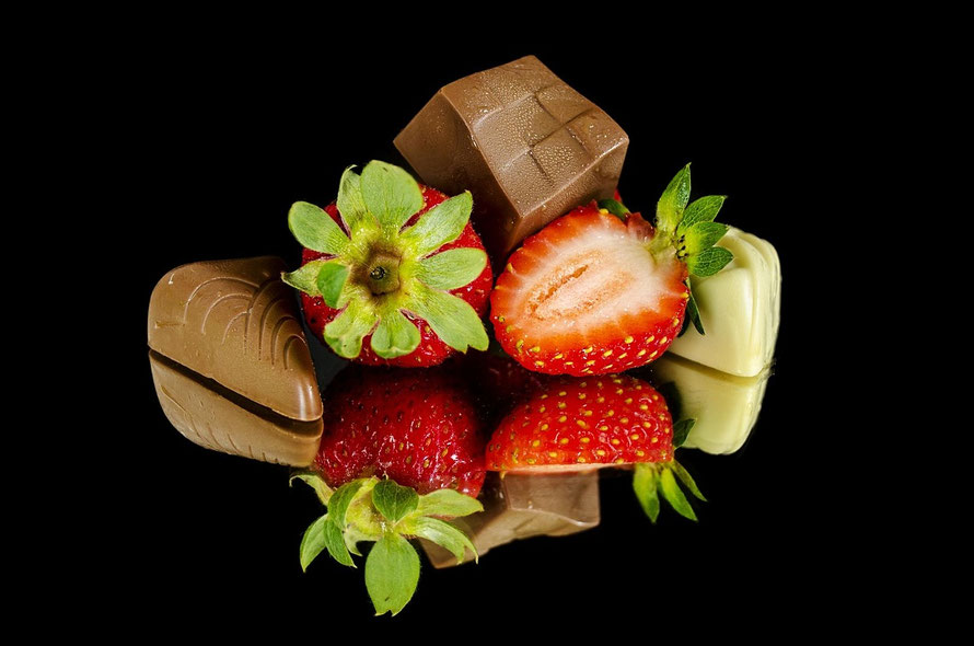 Pralinen und Erdbeeren auf einer spiegelnden Oberfläche