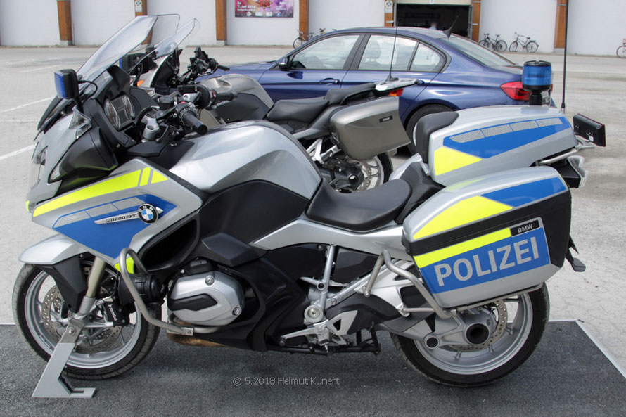 Im Hintergrund ein ziviles Polizeimotorrad zur Verkehrsüberwachung.
