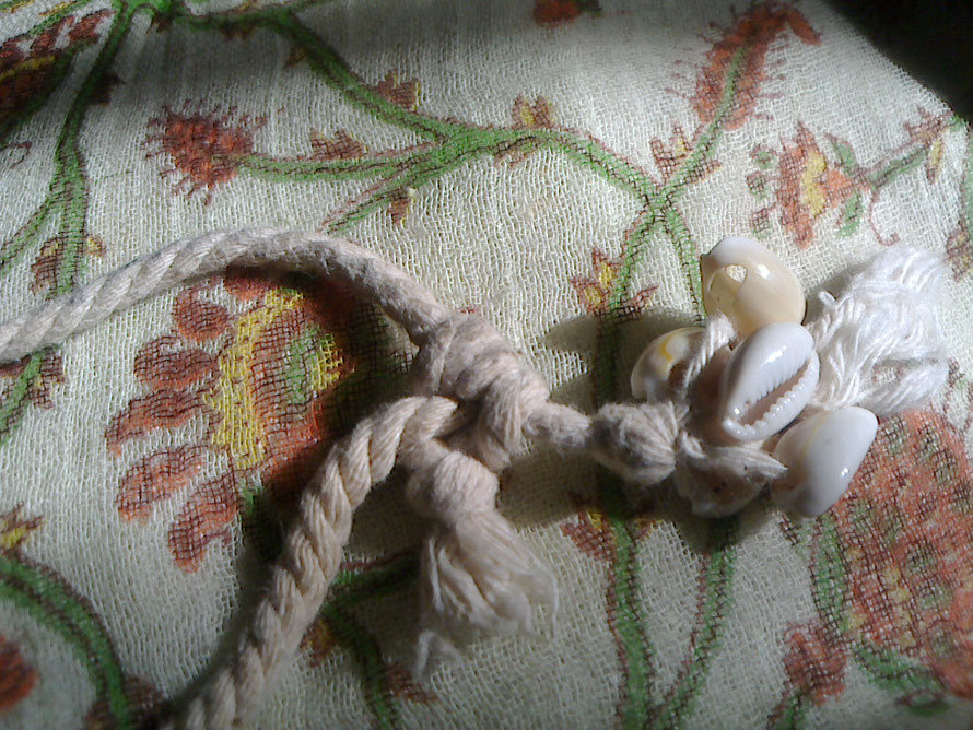 テントを張るときに使う、自在結びです。伸び縮みさせる糸の反対側の糸に、貝殻でできたビーズをあしらって、首の後ろに結び目があっても、サイズ調節がし易くなっています。