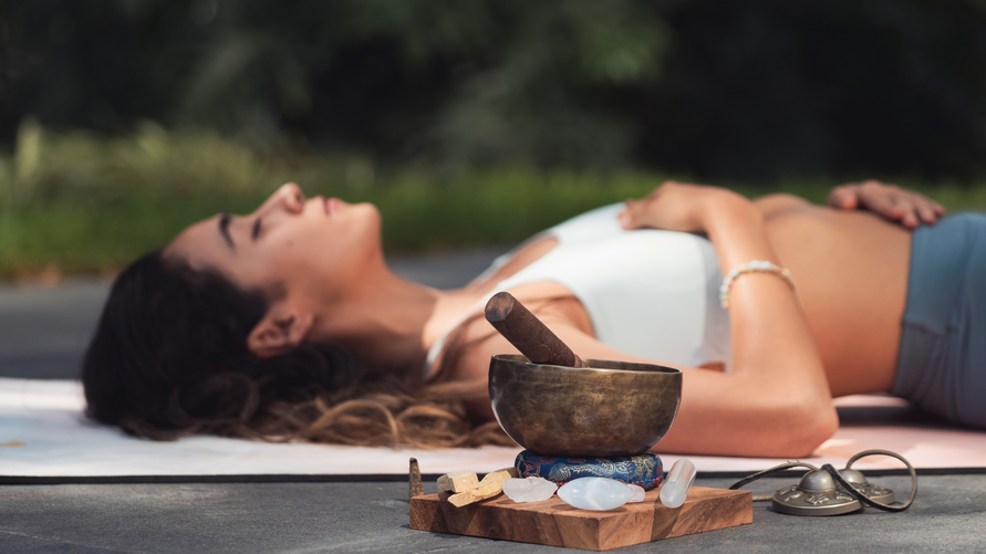 eine Frau liegt entspannt auf ihrer Meditationsmatte und atmet