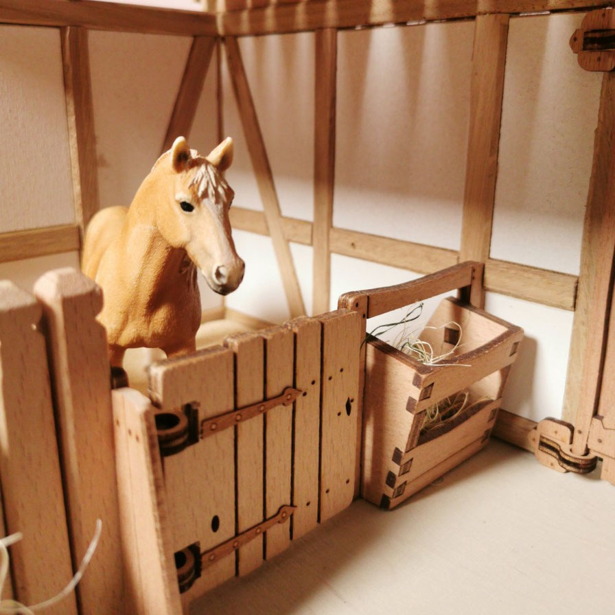 Pferdebox aus Holz mit Drehtor und Heuraufe in Spielszene mit Modellpferd