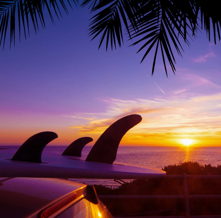 Surfboard auf dem Autodach bei Sonnenuntergang