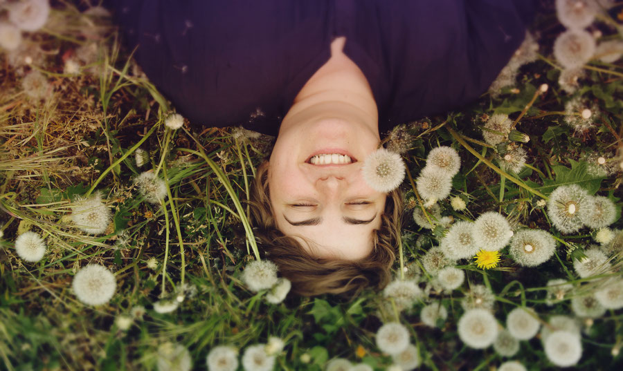 Woman in a field of flowers, grinning.