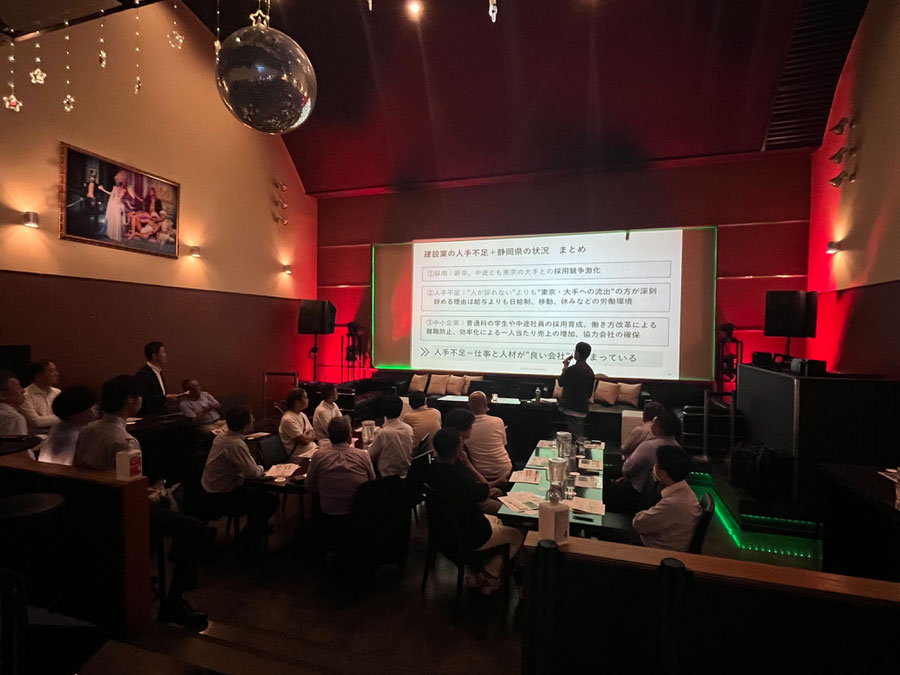 建設業応援セミナーにて、講師がスクリーンを使って解説している講演シーン