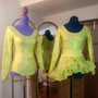 Sur l'image, deux mannequins portant deux ensembles latinos faits en lycra jaune et or composés d'un justaucorps manches longues et une petite jupe avec un volant au fond. Création Fil et Paillettes.