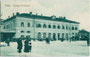 Trento - Stazione Ferroviaria (dt. Trient – Bahnhof) an der Piazza d'Armi (dt. Exerzierplatz), heute Piazza Dante (Alighieri). Heliogravüre 9 x 14 cm; Verlag Fototipia Alterocca – Terni 1921, postalisch befördert 1919.  Inv.-Nr. vu914hg00043