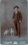 Verbindungsstudent in Hemd mit Vatermörder (Stehkragen), dreiteiligem Anzug mit Bierzipf, Fritzstock und Hut mit Hunden. Gelatinesilberabzug auf Untersatzkarton 10,6 x 6,8 cm (Visit-Format). F. Largajolli, Bozen um 1910.  Inv.-Nr. vuVIS-00110